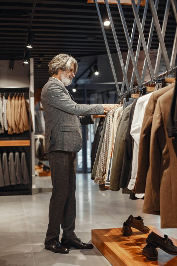 A man browsing clothes in a modern boutique store with a variety of suits on display.