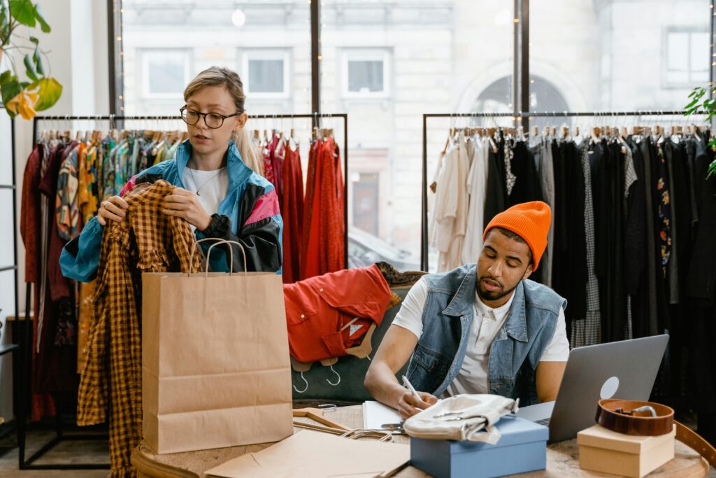 Retail workers organizing clothing in a boutique setting, fostering teamwork.